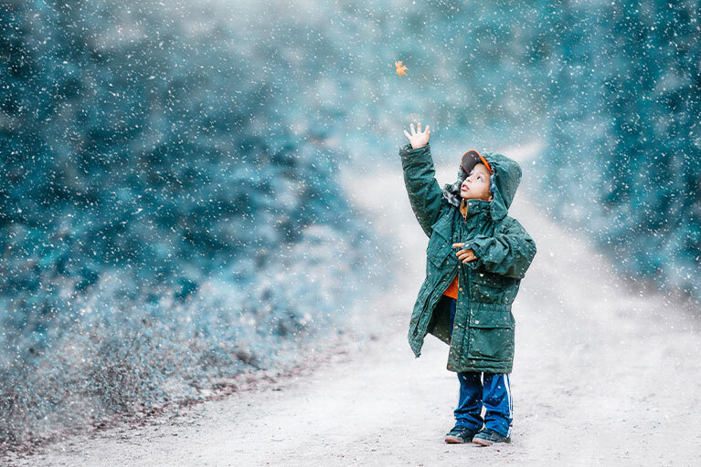 Kind im Schnee greift nach Blatt