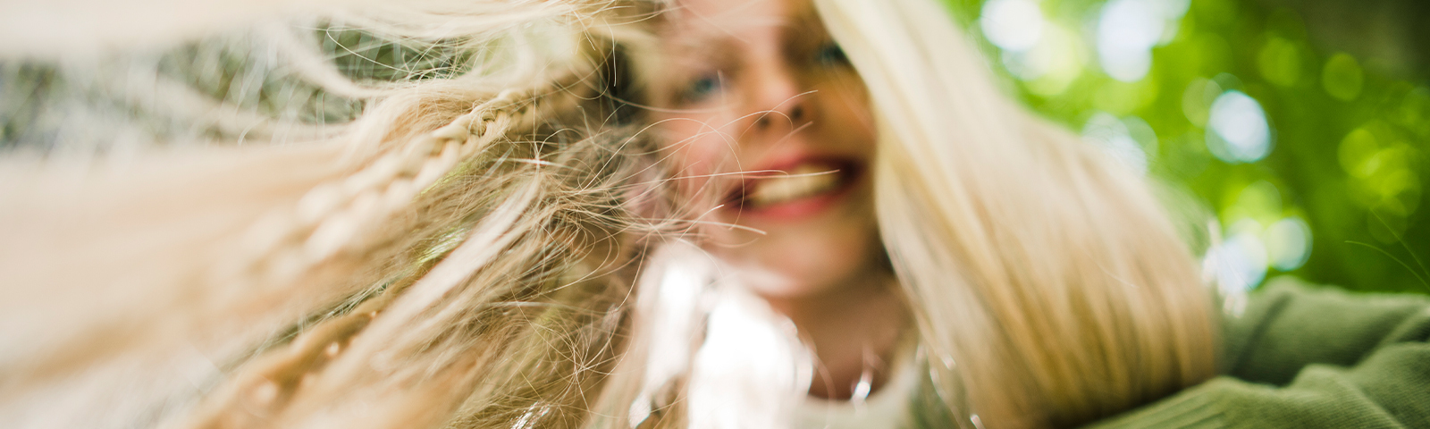 Kind mit langen Haaren blickt von oben in Kamera